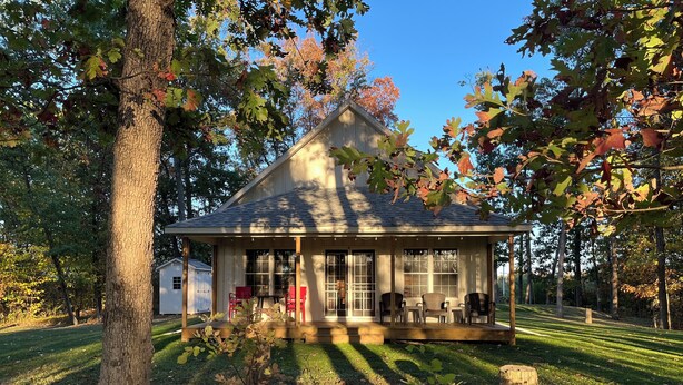 A small wooden cabin with a porch, surrounded by trees and a grassy yard. - Grey Goose Cottage In The Heart Of The FingerLakes (Keuka Lake Penn Yan)