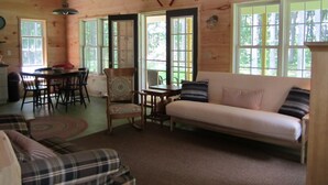 A cozy cabin interior with a plaid sofa, a dining table, and a chair. - Grey Goose Cottage In The Heart Of The FingerLakes (Keuka Lake Penn Yan)