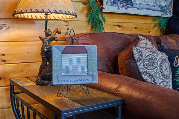 A cozy cabin-themed decor with a lamp, a bear figurine, and a 'Cabin in the Woods' sign on a table.