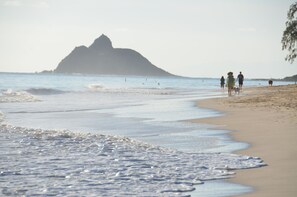 A beach with waves, a distant mountain, and people walking. - Steps to the Beach Guesthouse (Kailua)