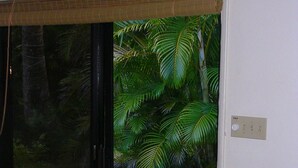 A room with a sliding glass door leading to a patio with a table and chairs, a patterned sofa, and a power outlet on the wall.