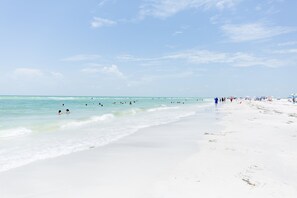 Ein Strand mit weißem Sand und klarem, blauem Wasser.