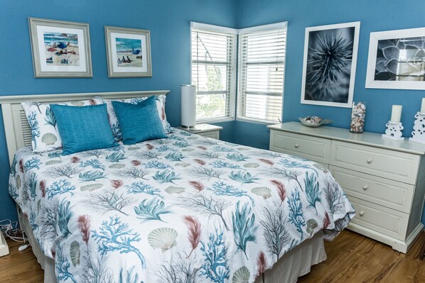 A bedroom with a bed, a nightstand, a dresser, and a window with blinds.