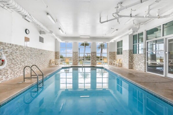 Une piscine intérieure offrant une vue dégagée sur les palmiers et agrémentée d’un mur carrelé.