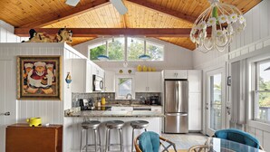 A kitchen with white cabinets, a stainless steel refrigerator, and a large window. - Ogunquit Cottage - walk to beach (Ogunquit)