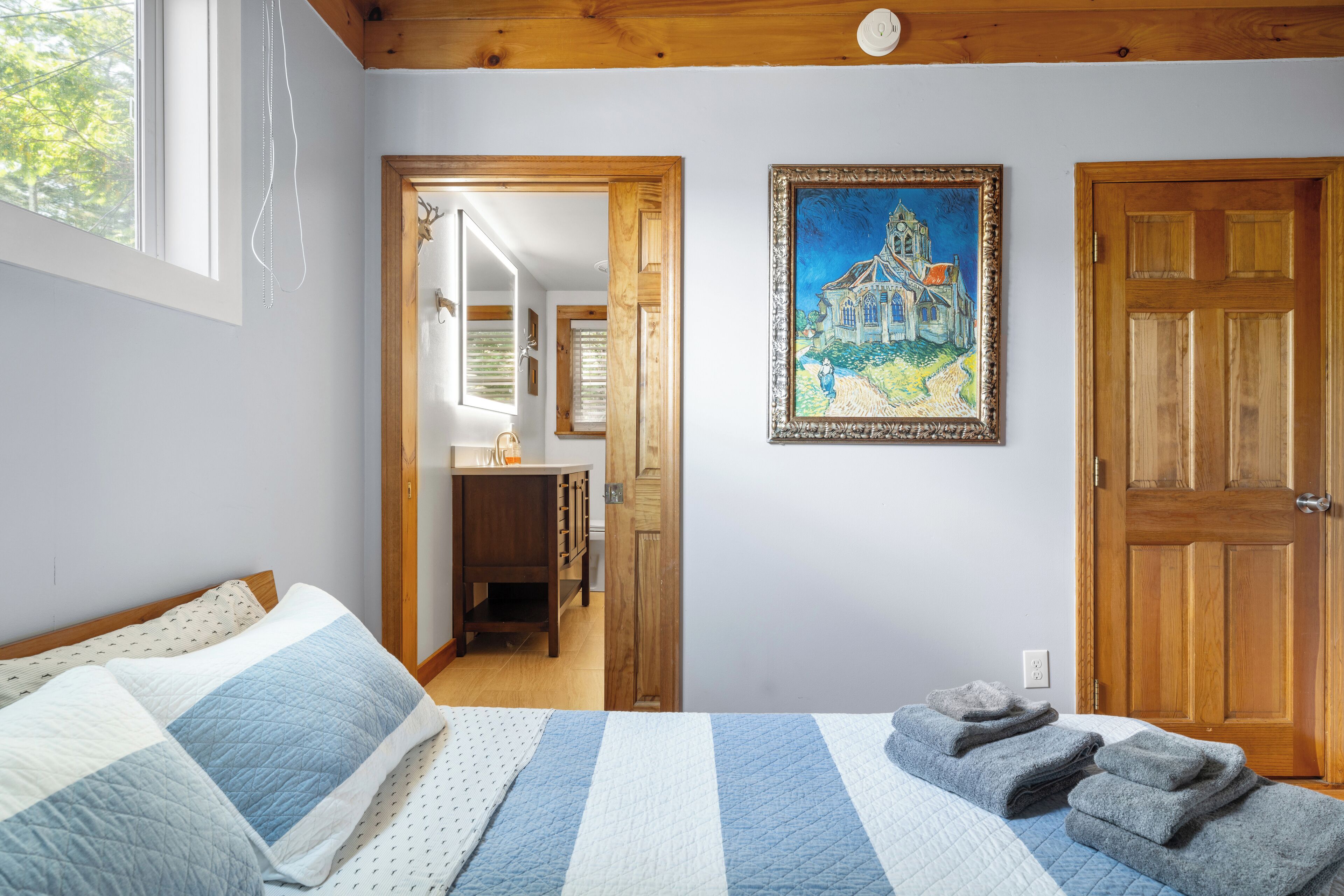 Une chambre à coucher avec un lit, un tableau et une porte en bois.