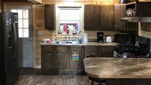 Una cocina funcional con armarios de madera, un lavamanos, una estufa y un microondas.
