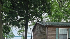 A cabin with a gravel driveway, a parked car, and a view of a lake. -  For Larger Groups Up To 24, Right on Reelfoot Lake--Private Dock And Pier. (Hornbeak)