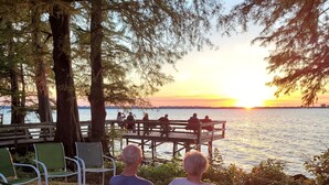 A couple sitting on a bench overlooking a sunset by a lake. -  For Larger Groups Up To 24, Right on Reelfoot Lake--Private Dock And Pier. (Hornbeak)