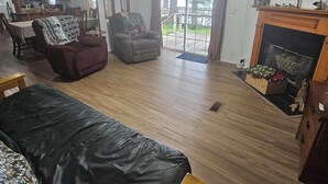A living room with a fireplace, a ceiling fan, and a view of the outdoors. -  For Larger Groups Up To 24, Right on Reelfoot Lake--Private Dock And Pier. (Hornbeak)