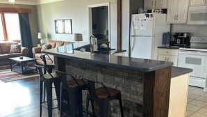 A modern kitchen with a central island, bar stools, and a dining area with a sofa and coffee table. - Right beside pool (Gatlinburg)