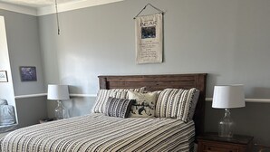 A bedroom with a wooden bed, striped bedding, two bedside tables with lamps, a ceiling fan, and a framed quote on the wall. - Right beside pool (Gatlinburg)