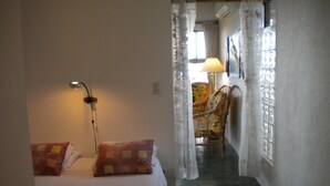 Una habitación de hotel con cama, lámpara, silla y ventana con cortinas.
