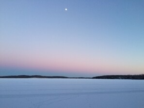 Paesaggio ghiacciato e piatto, con cielo sereno e la luna ben visibile.