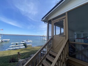 A lakeside cabin with a deck, a covered porch, and a view of the lake and boats. - 'Getg Inn' Comfortable Cozy Lakefront Property-Beautiful View (Penn Yan)