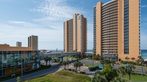 A modern hotel with a glass facade, a curved balcony, and a view of the ocean.