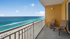 A balcony with a view of the ocean, two chairs, and a small table.