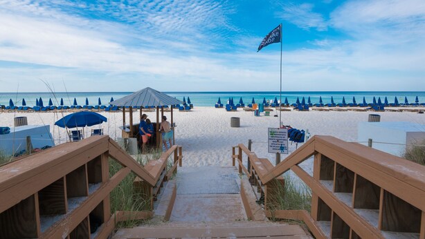 A beach with wooden walkways leading to beach umbrellas and lounge chairs.
