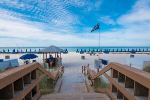 Ein Strand mit Holzstegen, die zu Strandsonnenschirmen und Liegestühlen führen.