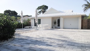 Une maison moderne avec une allée pavée, un garage et du mobilier d’extérieur.