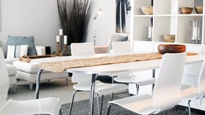 Un espace repas moderne avec une table blanche, des chaises blanches et un élément décoratif central.