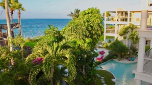 A resort with a pool, palm trees, and a view of the ocean. - Gorgeous second floor, ocean front with huge wrap around balcony!!! (Providenciales)