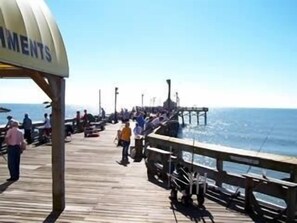 A wooden pier with people walking and sitting, overlooking the ocean. - UPDATED UNIT- Top beachfront resort, Clean, Ideal location, Pool n Beach close! (Myrtle Beach)