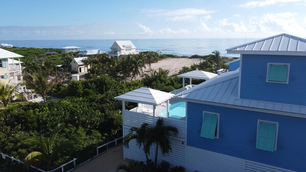 Une propriété située en bord de mer, dotée d’une piscine, d’un accès à la plage et de plusieurs bâtiments avec balcons.