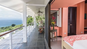 A balcony with a view of the ocean, a ceiling fan, and a table with a vase of flowers. - Villa Tortuga: Ocean Views Chef Included, Daily Housekeeping & Concierge Service (Quepos)