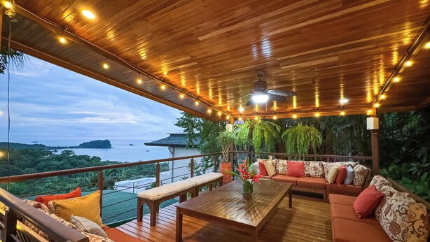 A wooden deck with a sofa, table, and bench, overlooking a scenic view. - Villa Tortuga: Ocean Views Chef Included, Daily Housekeeping & Concierge Service (Quepos)
