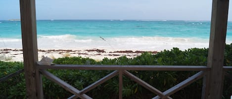 A wooden deck with a view of a beach and ocean.