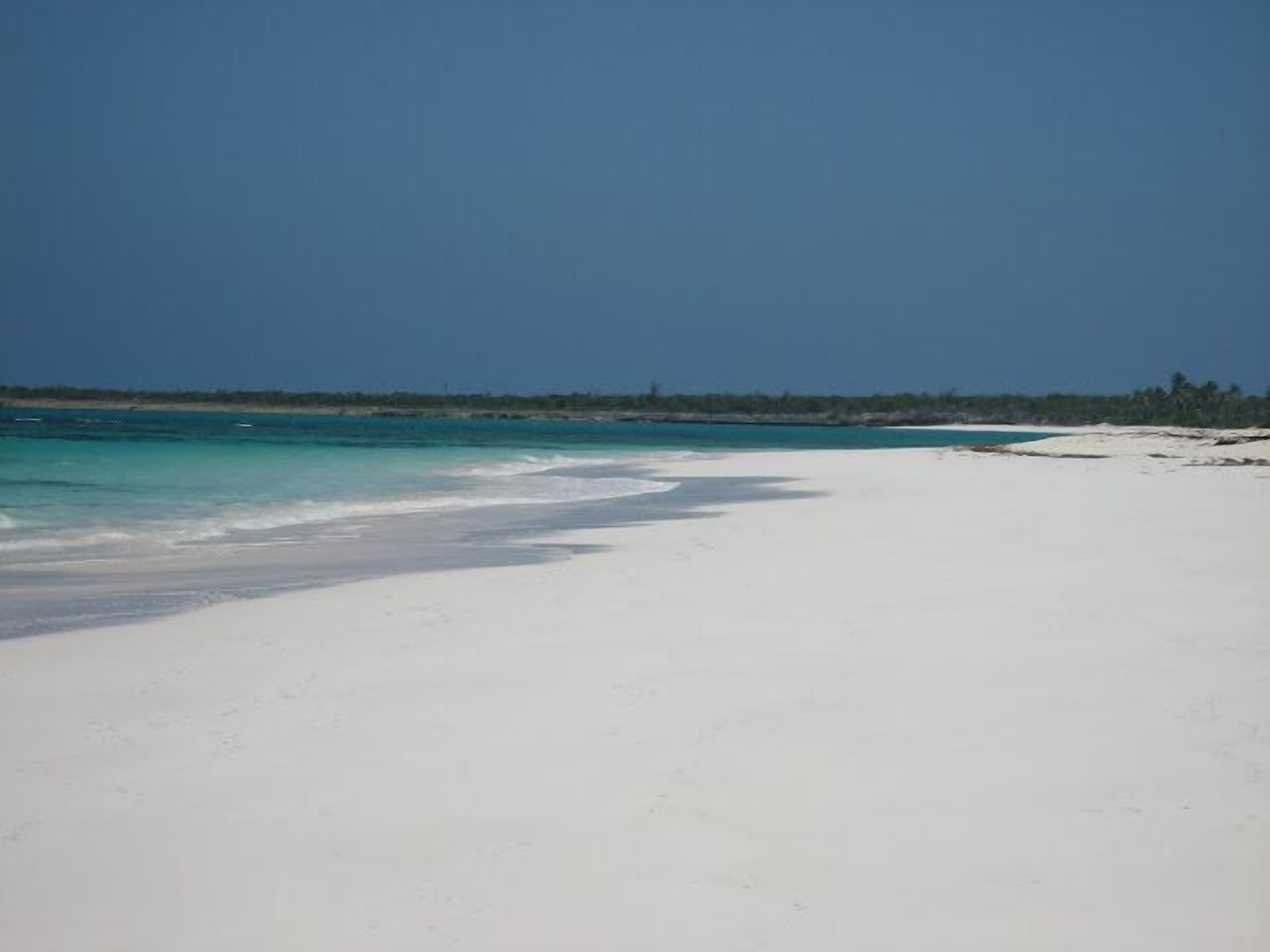 A beach with white sand and clear turquoise water.