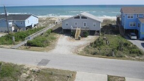 A beachfront property with a main house, a smaller structure, and a garage.