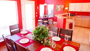 A dining area with a red table, white chairs, and a large plant centerpiece. - Starlight Villa of Sedona - 10% WEEKLY Discounts (Sedona)