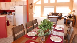 A dining area with a table set for four, surrounded by wooden chairs. A large potted plant is on the table, and there is a view of a living room in the background. - Starlight Villa of Sedona - 10% WEEKLY Discounts (Sedona)