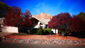 A house with a sloped roof, surrounded by red-leaved trees and a gravel driveway. - Starlight Villa of Sedona - 10% WEEKLY Discounts (Sedona)