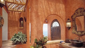 A rustic interior with a wooden staircase, a large potted plant, a wooden counter with a sink, and a door with a window. - Romantic 6,000 sq ft 3 Story Villa Magnificent Views from 4 Master Suite (Puerto Vallarta)