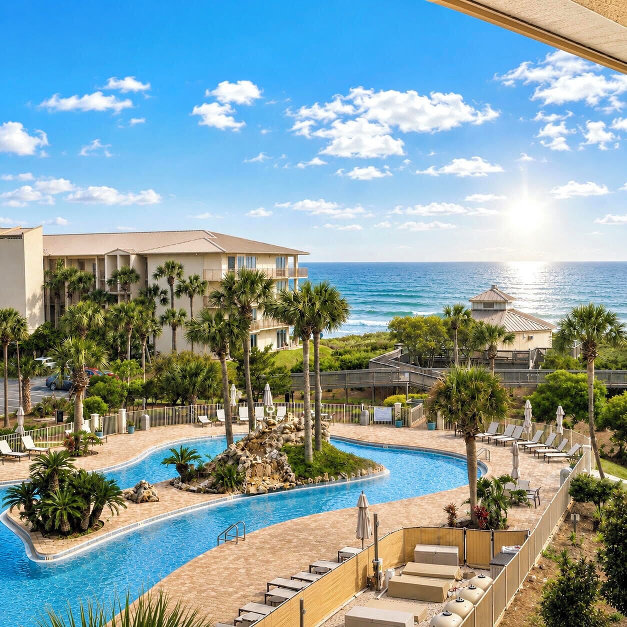 Un resort con piscina, palme e vista sull'oceano.