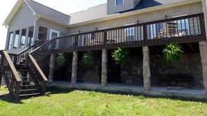 A two-story house with a covered porch, a staircase, and stone pillars. - Charming lakefront home for peaceful mornings and relaxing evenings. (Spring City)