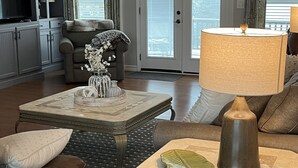 A living room with a sofa, coffee table, and lamp. There is a door with a view to the outside. - Charming lakefront home for peaceful mornings and relaxing evenings. (Spring City)