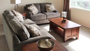 A living room with a grey sectional sofa, a wooden coffee table, and a painting on the wall.
