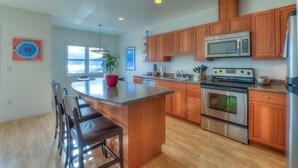 A modern kitchen with wooden cabinets, stainless steel appliances, and a central island with seating. - Water view! 
Luxury Port Suite -- walk to cafes, shops, galleries & beaches. (Eastsound)