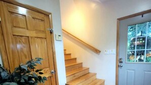 En trappa med trästeg som leder upp till en liten plattform, en trädörr och en krukväxt.