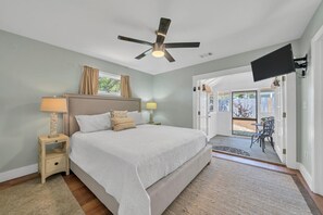 A bedroom with a large bed, two bedside tables, a ceiling fan, and a TV mounted on the wall. - Gulf views Beach House & Large Private Pool, 2 owner suites; Walk 2 Beach (Panama City Beach)