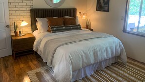 A bedroom with a bed, a nightstand, a lamp, a mirror, a window, and a door. - Starview Lodge: Quiet Mountain Home Bordering State Forest (Cobb)