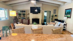 A spacious living room with a fireplace, a television mounted on the wall, and a dining area with a marble countertop. - Starview Lodge: Quiet Mountain Home Bordering State Forest (Cobb)