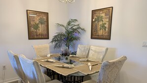 A dining area with a glass table, beige tablecloth, and floral chairs. - A Great Location Five Miles From Major Theme Parks (Kissimmee)