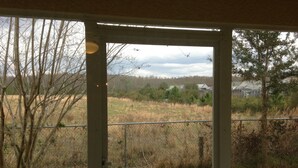 A view through a glass door of a grassy area with trees and a fence. - A Great Location Five Miles From Major Theme Parks (Kissimmee)