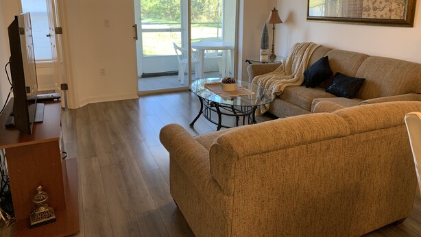 A living room with a sofa, a glass coffee table, and a television. - A Great Location Five Miles From Major Theme Parks (Kissimmee)