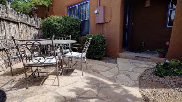 An outdoor patio with stone flooring, metal chairs, and a table. - Casita D - 2 Bed, 2 Bath (Single Level) (Santa Fe)